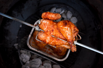 Grillhuhn am Drehspie&szlig; &uuml;ber der Glut im Kugelgriller (Grillh&auml;hnchen, Grillhendl)