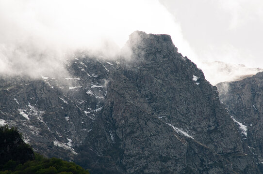 Fog on Mount Khustup granite face with spring snow