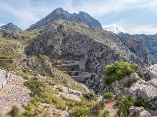 Serpentine road to Sa Calobra, Mallorca, winding road snakes through rugged mountains, with a few hikers enjoying the scenic route, Majorca