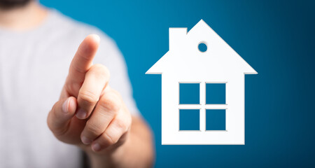 A hand is touching a house icon, representing real estate, homeownership, investment, and the dream of owning a home. Perfect for illustrating p