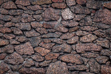 Textured granite boulder masonry with deep, dark joints. Natural stone texture