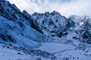 A harsh autumn-winter landscape in the mountains. A pond begins to freeze.
