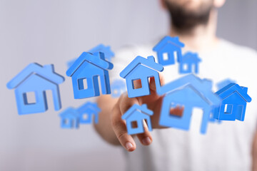 Conceptual image of a hand reaching out towards blue houses, symbolizing real estate, home ownership, or property investment.  Focus on choice a