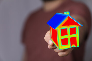 A person's hand holding a 3D model house illustrating energy efficiency. Showcasing concepts of...