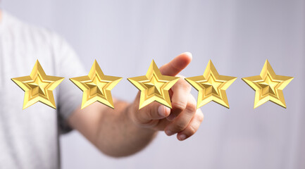 A person's hand pointing at five golden stars, representing rating, feedback, and review, ideal for illustrating quality, excellence, and succes