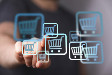 Close up of a hand touching shopping cart symbols, representing online shopping, sales and...