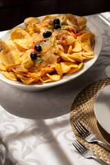 The "Bacalhau com Cebolada", a traditional Portuguese dish made with fried codfish topped with sautéed onions, peppers, and olives, served with crispy round potato chips.