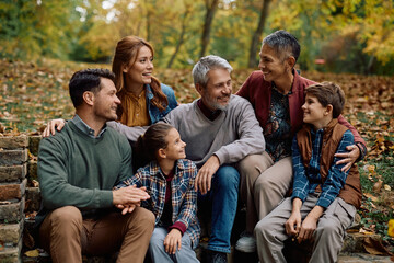 Happy extended family talking while enjoying in autumn day in park.