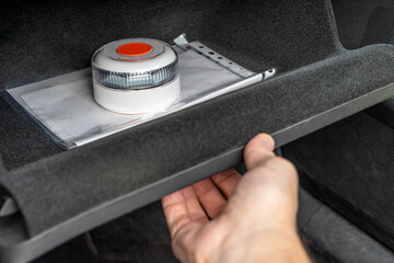 Hand opening car glove compartment with connected V16 emergency warning beacon with GPS geolocation
