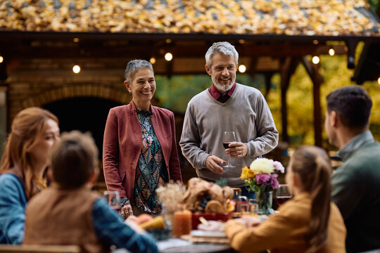 Happy mature couple holding toast while celebrating Thanksgiving with their family.