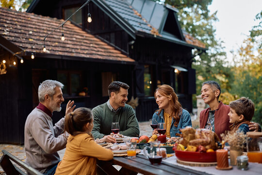 Happy multi-generation family enjoying in conversation while gathering on Thanksgiving.