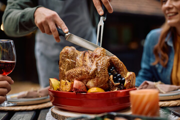 Close up of father carving turkey during Thanksgiving dinner with his family.