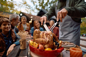 Close up of father carving roast Turkey during family Thanksgiving celebration.