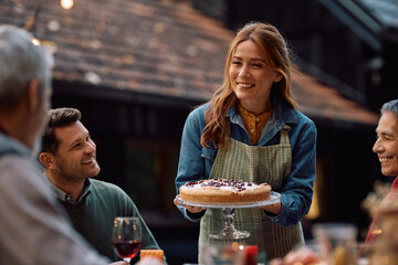 Happy woman serving Thanksgiving pie to her extended family.