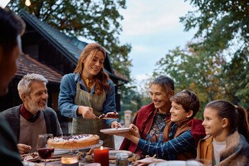 Happy multi-generation family enjoying in Thanksgiving pie on patio.