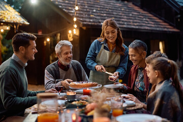 Happy extended family having Thanksgiving pie for dessert after dinner on patio.