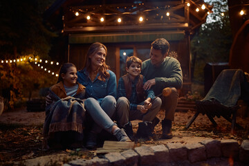 Happy family enjoying in autumn evening by bonfire.