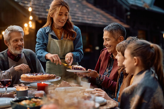 Happy mother serving sweet pie during family meal on Thanksgiving. - Powered by Adobe