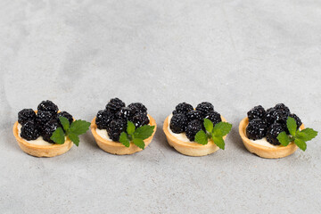 Mini blackberry tart. With custard. Decorated with mint. Light gray background. Copy space