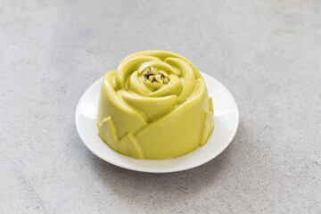 Vegan Pistachio cream dessert in the shape of a rose. Decorated with chopped pistachios.