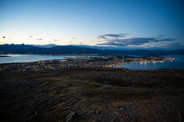 View from Storsteinen, stunning evening view of Tromso, Norway with mountains in the background, illuminated by the setting sun, at the top of Storsteinen