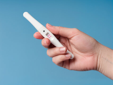 A woman's hand holding a positive pregnancy test with two pink stripes on a blue background - Powered by Adobe