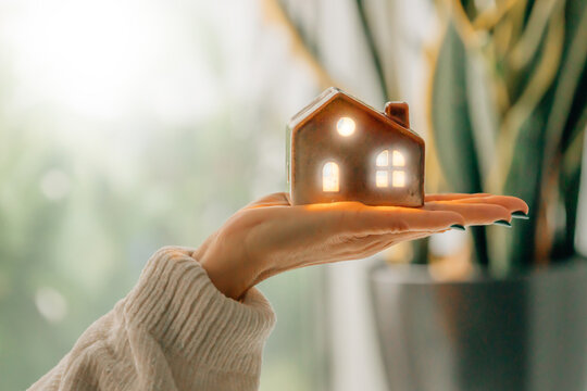 hand holding a house with light and lighting, energy