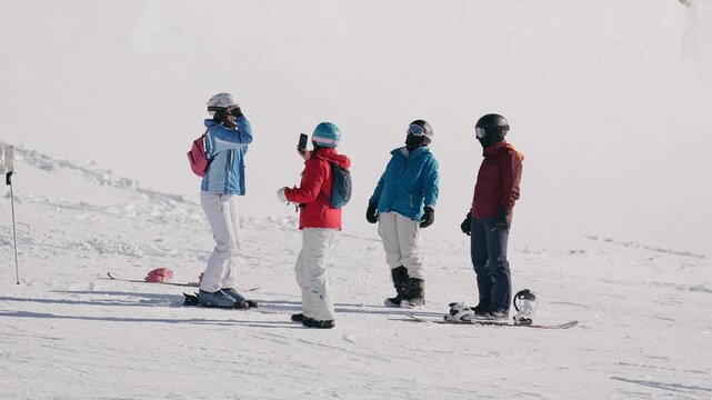 Group of friends taking photos while skiing on a snowy mountain slope. A lively winter sports and tourism scene full of friendship and fun.