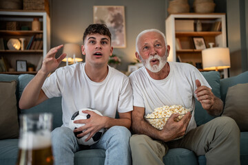 Grandfather and grandson watching soccer on television