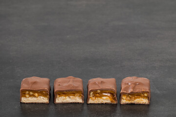 Chocolate Candy bar with nougat and caramel, peanuts and hazelnuts.  Dark background. Copy space