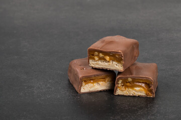 Chocolate Candy bar with nougat and caramel, peanuts and hazelnuts. Close up. Dark background