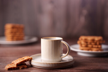 a calm morning scene featuring a ceramic mug of coffee and stack of biscuits on rustic wooden table with soft focus background for cozy ambiance, peaceful, appetizing, aligned, background