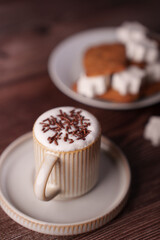 cozy coffee scene with a cappuccino topped with chocolate sprinkles and marshmallows, set on a wooden table with biscuits and a warm palette creating a warm, inviting ambiance, ambiance, relaxed