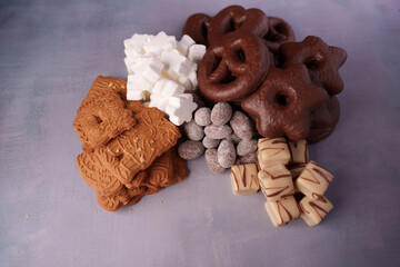 a vibrant assortment of festive cookies and confections featuring chocolate pretzels, almond biscuits, crispy wafers, drizzled sweets, and marshmallow treats on a textured surface, yummy, hard, soft