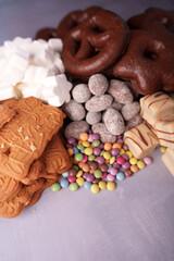 assortment of delicious sweet treats featuring chocolate pretzels, spiced biscuits, colorful candies, sugary marshmallows, and creamy confections on a soft pastel background, decadent, lavish