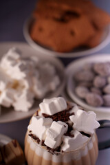 cozy close-up: whipped cream-topped hot cocoa with star-shaped marshmallows and assorted cookies on a softly lit dessert table setting, inviting, luxurious, festive, cafe, pastry, brownie, plated