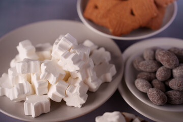 assortment of marshmallows, cookies, and chocolates on plates in soft pastel setting with gentle lighting and delicate arrangement highlighting textures, blur, focus, hospitality, gathering