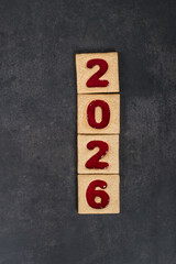 New Year 2026. Square cookies with red marmalade filling in the shape of the numbers 2026. Dark background. Top view	