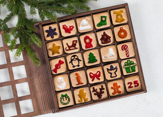 Advent Calendar. 25 festive square cookies with colored curly marmalade filling. In a wooden gift box. White background. Top view