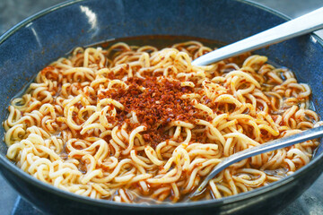 Instant noodles fork and spoon in a bowl. Spicy noodle soup. Asian food style.
