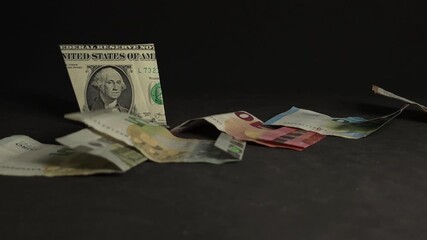 The domino effect with falling euro banknotes revealing a US dollar in slow motion