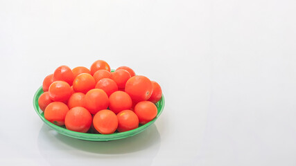 Close-up of a pile of colorful cherry tomatoes in a bowl, on a white background with plenty space for copy text.