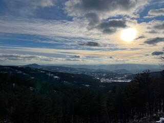 Sun Setting Over Snowy Mountain Landscape and Pine Forest