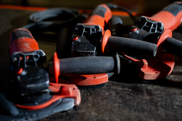 Set of red industrial angle grinders placed on workshop table showing power tools used for metal...