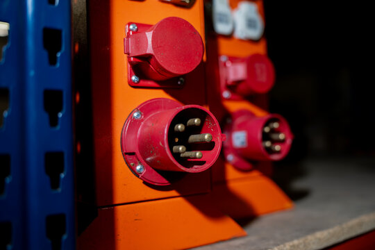 Red industrial electrical sockets mounted on orange box showing power supply connections used in workshops, factories, or construction environments for reliable energy access