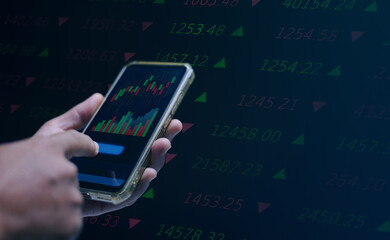 Concept of stock trading and financial investment. Hand using smartphone with digital chart showing rising and falling prices. Online trading, market analysis and economic data technology.