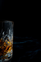 Lowball whisky glass in dark studio environment on dark marble table. with negative space and copy space for adding text and effects.