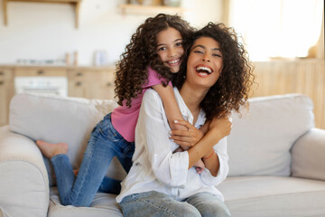 Obraz premium Family, love concept. Mother and daughter having fun at home, hugging, spending time and laughing while sitting on couch in living room