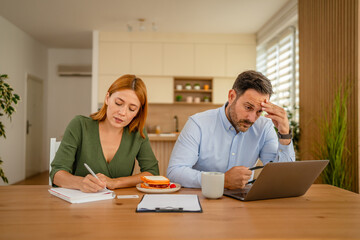 Couple managing home finances, stressing over bills and budget