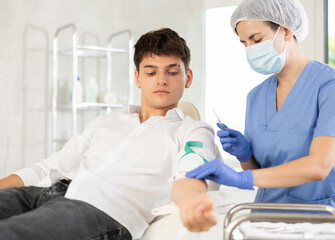 Obraz premium Young brunette guy lying at examination couch before intravenously injection at treatment room